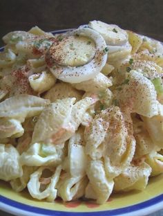 a plate full of pasta with onions and seasoning on the top, sitting on a table