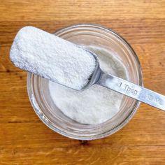 a spoon with sugar on it sitting in a jar