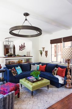 a living room with blue couches and colorful pillows on the back of the couch