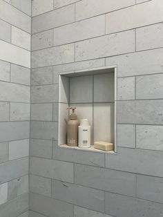 a bathroom with white tile and gray walls, including a shower niche in the wall