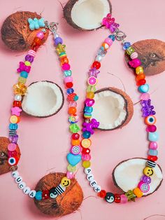 two coconuts and some beads on a pink surface with an animal charm necklace in the middle