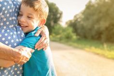 an older woman hugging a young boy on the side of a road in front of trees