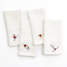 three white towels with birds on them and one has skis embroidered on the front