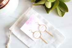 a pair of earrings sitting on top of a white napkin next to a potted plant