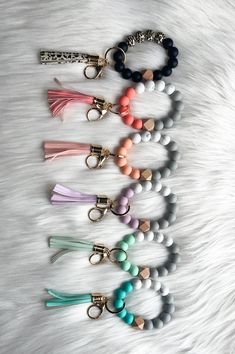 six key chains with tassels on them sitting on top of a white fur surface