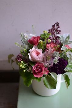 a white vase filled with flowers on top of a green table