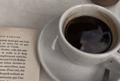 a cup of coffee sitting on top of a saucer next to an open book