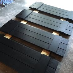 three pieces of black wood sitting on top of a floor next to each other with holes in them