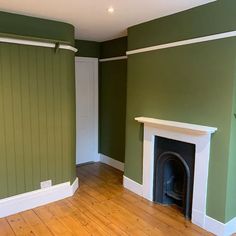 an empty living room with green walls and wood floors