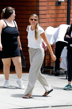 two women walking down the street with one holding her hand in her other's pocket