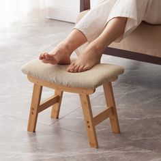 a woman is sitting on a stool with her feet up and one foot resting on the seat