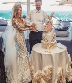 a man and woman standing next to each other in front of a table with a cake on it