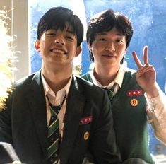 two young men in school uniforms posing for the camera with their fingers up and smiling