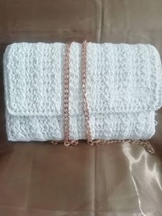 a white crocheted purse sitting on top of a bed