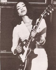 a woman holding a guitar in her right hand