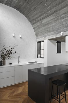 a modern kitchen with white cabinets and black counter tops is featured in this image, along with an arched ceiling