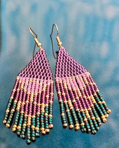 two pairs of beaded earrings sitting on top of a blue cloth covered table next to each other