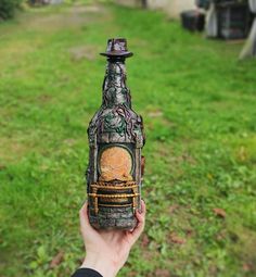 a person holding up a bottle with an image on it in front of some grass