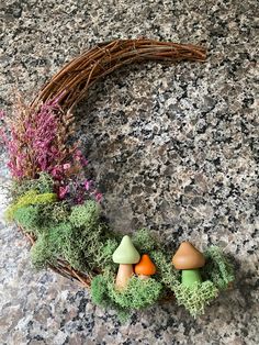 an arrangement of mushrooms and plants in a wicker basket on a granite countertop