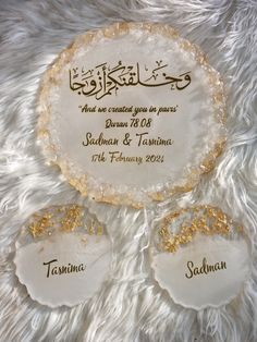 two white and gold wedding coasters sitting on top of a fur rug