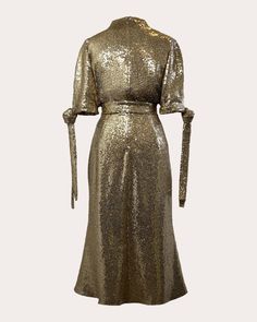 a gold sequinned dress with long sleeves and a tie at the waist, on a white background