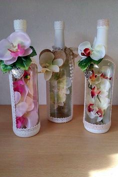 three vases with flowers in them sitting on a table next to each other,