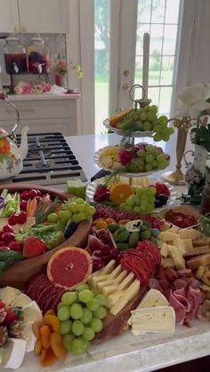 an assortment of cheeses, fruits and meats on a table in a kitchen