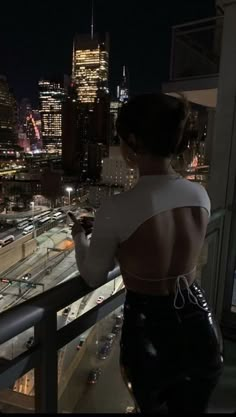 a woman standing on top of a balcony next to a city