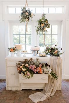 a table with flowers and cake on it in front of a white window sill