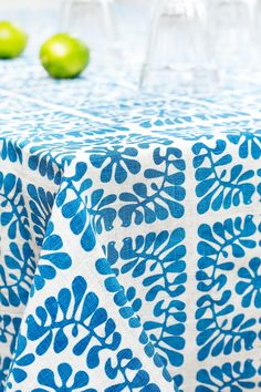 the table cloth is blue and white with green apples in the background