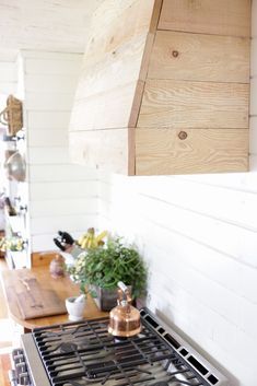 a stove top oven sitting inside of a kitchen next to a wooden counter and wall