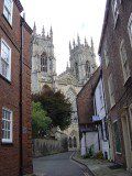 a narrow street with brick buildings on both sides and an old cathedral in the background