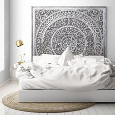 a large white bed sitting in a bedroom next to a wall mounted headboard with an intricate design on it