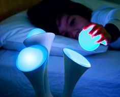 a person laying in bed with two lights on their feet and one hand reaching for something