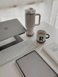 a tablet, coffee mug and keyboard on a desk