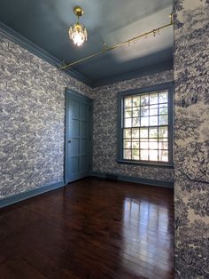 an empty room with wood floors and blue wallpaper on the walls is seen in this image