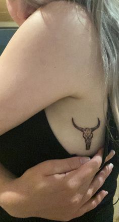 a woman with a bull skull tattoo on her shoulder