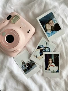 a pink polaroid camera sitting on top of a bed next to pictures and a pen