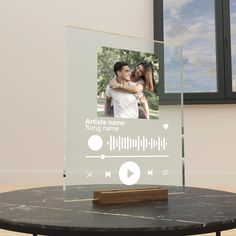 an acrylic photo frame on a table in front of a window