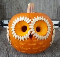 an orange pumpkin decorated with white flowers and two large eyes, sitting on a chair