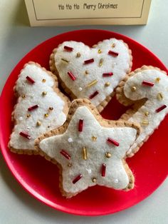 three decorated cookies on a red plate next to a box of christmas crackers with sprinkles