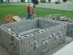 two men are standing in front of a cinder block structure that's being built