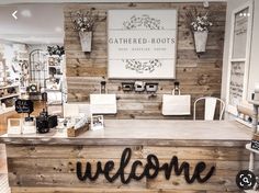 a welcome sign is displayed on the counter in a store with wooden walls and windows