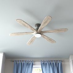 a ceiling fan in a room with blue curtains