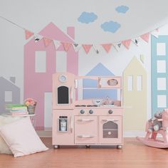 a child's play kitchen with pink, blue and yellow painted houses on the wall