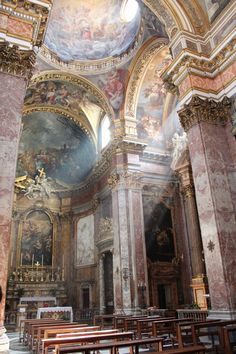 the interior of an old church with paintings on the walls and pews in it