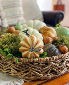 a wicker basket filled with pumpkins and gourds on top of a table