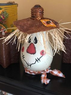 a decorated egg with a scarecrow hat on it's head sitting on a table