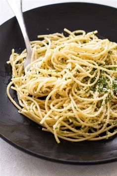 a black plate topped with spaghetti and parsley