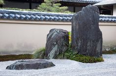 two large rocks sitting in the middle of a gravel area with grass growing between them